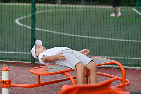 a boy on the playground does abdominal exercises