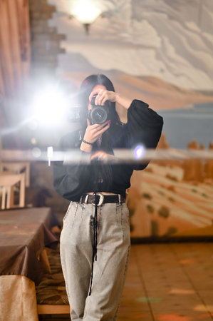 A photographer girl takes pictures with a camera with a flash indoorsの写真素材