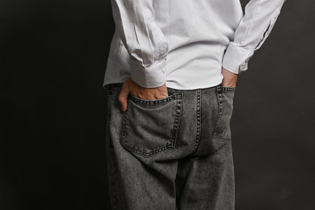 The man's hands are tucked into the back pockets of his trousers, thumbs out.