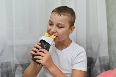 The boy is eating a delicious sandwich.の写真素材