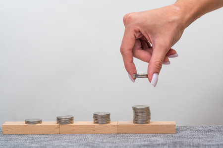 The hand puts money and coins in piles, the amount grows.の写真素材