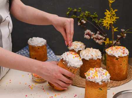 a woman sprinkles a Easter cake with sweet sprinkles.