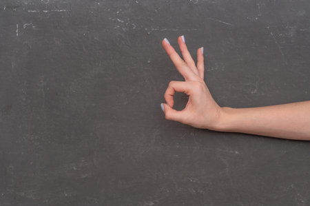 A woman's hand signals - it's okay. close-up on a gray background. The concept