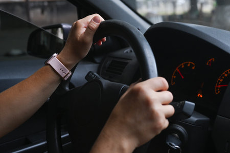 womens hands on steering wheel grip, showing focus and control. person is driving through smooth,...