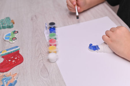 Creative hobby, Little artist paints with brush in bright colors simple brushwork on gypsum toys. girl paints plaster figure of snowman. DIY Christmas ornaments.の写真素材