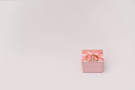 Pink gift box with two wedding rings inside, creating elegant scene of engagement or wedding...