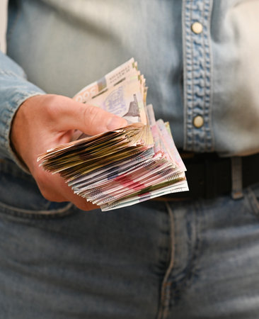 vertical photo of a large wad of money in a man's hand. Person holds thick bundle of banknotes in hand, showing large amount of cash and financial concept. the Ukrainian hryvnia is in men's hands.の写真素材