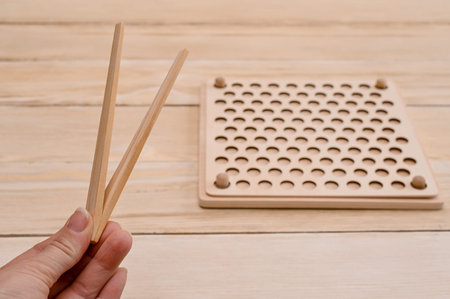 Wooden Montessori sorting board. In the hands of a wooden tweezers. New anti-stress and logic toys for children and adults. Preschool education.の写真素材