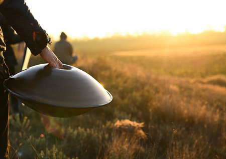 hang in the hand of a man on the background of a summer field. handpan in a golden field. A man carries a hang at dawn. hang musical instrument.の写真素材