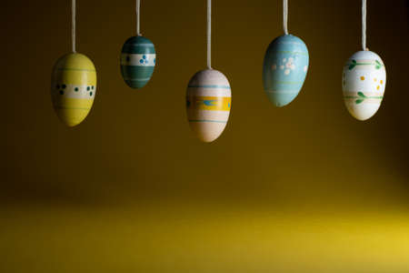 Happy Easter greeting card background with empty copy space. Colorful Easter eggs hanging over yellow background.の写真素材