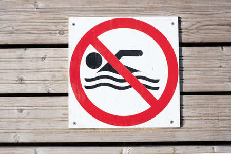Swimming prohibited warning sign on wooden background. "No swimming" sign on a boat dockの写真素材