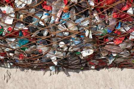 PÃ¤rnu, Estonia - June 5, 2021: Large wire trash container for collecting plastic waste from beach. Garbage bin for used plastic bottles and other waste. Full frame.のeditorial素材