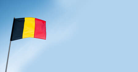 Belgian flag waving in wind. Flag of Belgium on blue sky background. Empty copy space.の写真素材