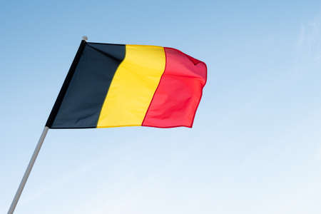 Belgian flag waving in wind. Flag of Belgium on blue sky background.の写真素材
