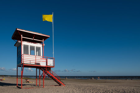 PÃ¤rnu, Estonia - July 11, 2021: G4S lifeguard tower with yellow flag indicating swimming is dangerous for poor swimmers.のeditorial素材