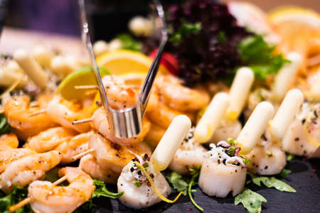 Grilled tiger prawns and baked scallops with lemon-saffron sauce. Delicious professional looking food and snacks served at catering event or party buffet style.の写真素材
