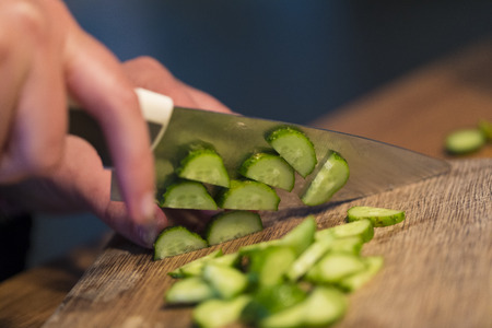 Someone cutting a cucumber on a cutting boardの写真素材