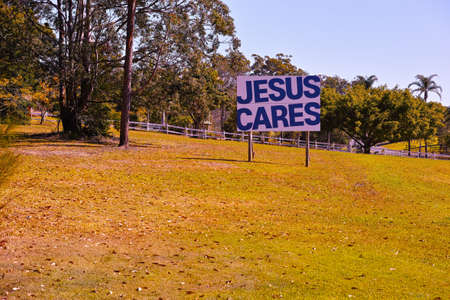 Big religious sign on grass with Christian message. Proselytising roadside sign on the lawn with a background of a fence and tropical Australian trees.の写真素材