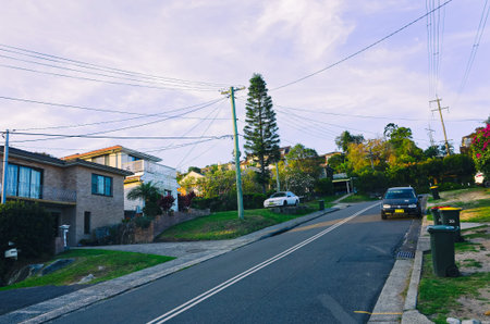 Typical suburban Australia street with sidewalk, residential buildings, grass and trees. Suburb of Brookvale in the Northern Beaches area of Sydney, New South Wales, Australiaのeditorial素材