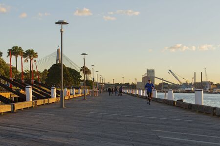 Sydney, Australia - June 24, 2017: A runner and pedestrians at Darling Island Park wharf in Sydney with the Anzac Bridge in the backgroundのeditorial素材
