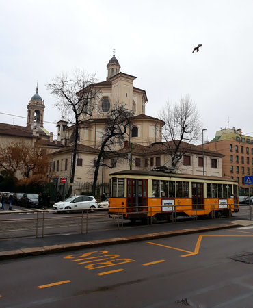 Vintage Yellow Tram And Church Behind It On The Street Of Milan, Italyのeditorial素材