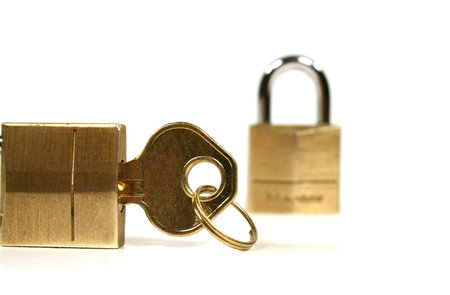 Two small brass padlocks with a key isolated on a white background.