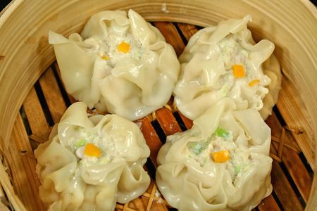 Delicious steamed dim sums freshly steamed in a bamboo steamer.の写真素材