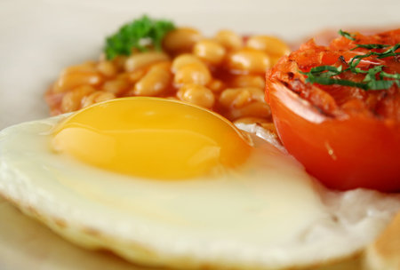 Breakfast of grilled bacon, tomato, egg and baked beans.の写真素材