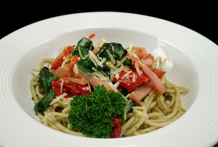 Spaghetti with bacon, pesto, sundried tomato and  spinach topped with parmesan cheese.の写真素材