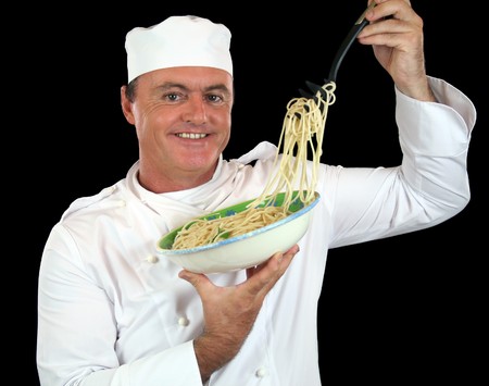 Chef lifting cooked spaghetti from a bowl with a pasta fork.の写真素材