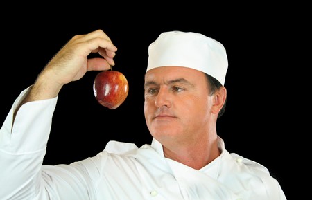 Chef holds up healthy apple and contemplates its use.の写真素材