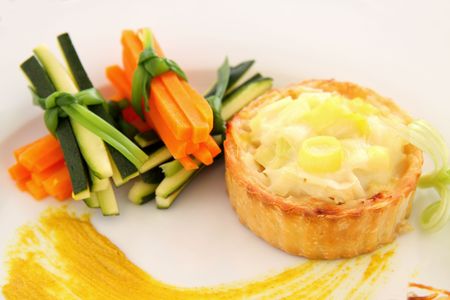 Fresh baked cheese and leek tart with vegetable bundles.の写真素材
