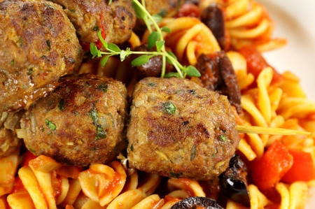 Delicious beef meatballs on tomato and olive pasta.の写真素材