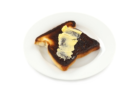 A piece of burnt toast spread with butter.の写真素材