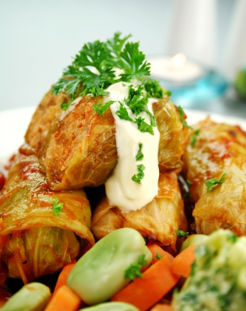 Baked pork and cabbage rolls with carrots and broad beans with a tomato sauce.の写真素材