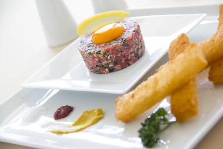 Delicious steak tartare with raw egg with lemon ready to serve.の写真素材