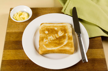 Slice of toast with Smile carved into it with butter ready for breakfast.