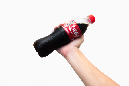 CHIANG RAI, THAILAND 2nd May 2016, Hand hold a bottle Coca-Cola on white background. Coca Cola drinks are produced and manufactured by The Coca-Cola Company.のeditorial素材