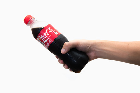 CHIANG RAI, THAILAND 2nd May 2016, Hand hold a bottle Coca-Cola on white background. Coca Cola drinks are produced and manufactured by The Coca-Cola Company.のeditorial素材
