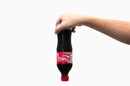 CHIANG RAI, THAILAND 2nd May 2016, Hand hold a bottle Coca-Cola on white background. Coca Cola drinks are produced and manufactured by The Coca-Cola Company.のeditorial素材