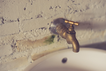 On the white wall the old brass faucet made with vintage filter.の写真素材
