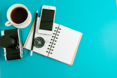 Creative flat lay photo of workspace desk with coffee, blank notebook, smartphone and film camera with copy space background, minimal styledの写真素材