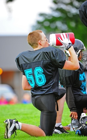 September 14, 2011 American Football (Youth 7-8th Grade) Hillsboro Oregon Century HS youth V Forest Grove Jr High Titans. Century Jaguar #54 takes a drink to hydrate himself during the half time huddle.  Final score 39-19 Forest Grove.のeditorial素材