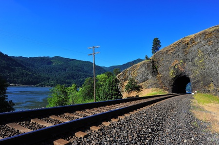 Railroad tracks leading to a natural face portal tunnel along the Columbia River Gorge on the Washington state side.の写真素材