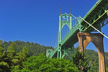 An aging tall bridge spans high above the trees over the river front park, this bridge is high...