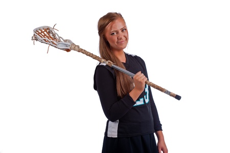 High school girls lacrosse player isolated on a white background and dressed in a black uniform holds her stick over her shoulder as she looks over towards the camera with the free hand on her hip の写真素材