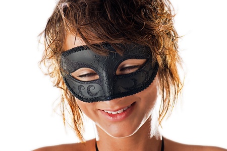 A beautiful young woman with wet hair and an endearing smile behind the black mask she is wearing and isolated on a white background の写真素材