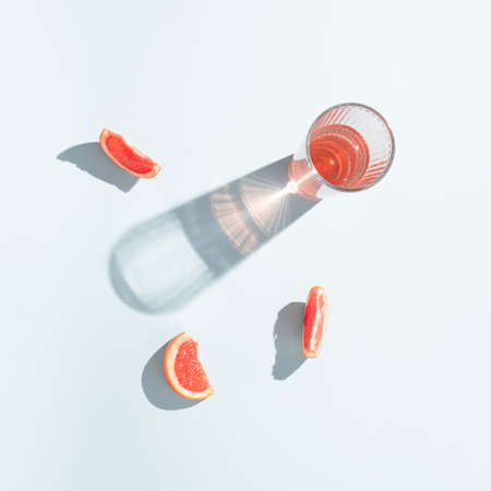 A glass of grapefruit juice with slices of fresh grapefruit on bright blue background. Minimal sunlit aesthetic.の写真素材