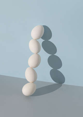 Minimal composition made of white Easter eggs against bright blue and gray background. Creative food concept.の写真素材