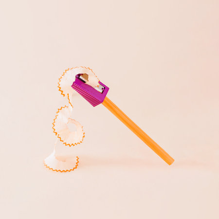 Creative composition made of orange pencil and purple pencil sharpener against a bright beige background. Minimal back to school concept.の写真素材